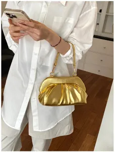 Borsa dorata plissettata con tracolla sottile, portata al braccio sopra un completo bianco