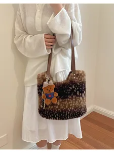 Model trägt eine braune Kunstfelltasche mit Hirschfleckenmuster, Lederhenkeln und Teddyanhänger