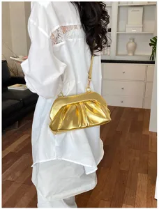 Borsa dorata plissettata con chiusura metallica e tracolla a catena, indossata con outfit bianco
