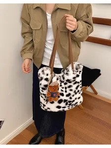 Model mit weißer Plüschtasche, schwarzen Flecken, braunen Henkeln und kleinem Bärenanhänger