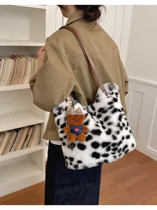 Frau mit weiß-schwarz gefleckter Plüschtasche, braunem Riemen und kleinem Bärenanhänger
