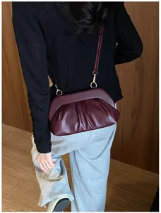 Vista posteriore di una borsa bordeaux arricciata, con tracolla regolabile e dettagli dorati