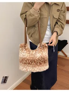 Eine Person trägt eine flauschige beige Tasche mit weißen Hirschflecken und langen braunen Riemen