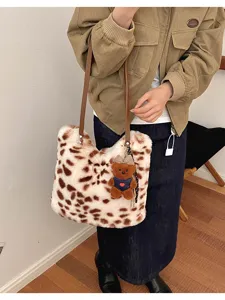 Gepunktete Plüschtasche über der Schulter, mit braunen Riemen und kleinem Teddybär-Anhänger.