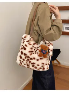 Plüsch-Shopper mit Fleckenmuster, braunem Riemen und Teddybär-Anhänger, über der Schulter getragen