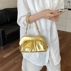 Borsa a spalla dorata effetto PU con pieghe e chiusura metallica, indossata su abito bianco