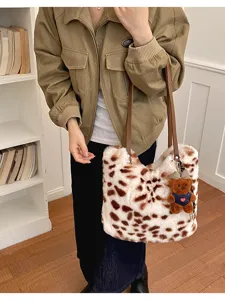Gepunktete Plüschtasche, am Modell mit braunen Riemen und kleinem Teddybär-Anhänger getragen