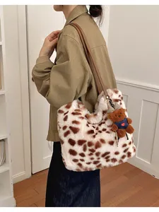 Seitenansicht einer flauschigen Tasche mit Fleckenmuster, braunem Schulterriemen und Teddyanhänger
