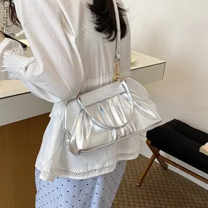 Borsa argentata in similpelle arricciata con dettagli dorati, indossata a tracolla dalla modella