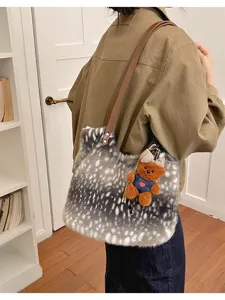 Seitenansicht einer grau-weißen Plüsch-Schultertasche mit braunem Riemen und Teddyanhänger