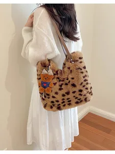 Am Model: Eine flauschige Schultertasche mit Leopardenmuster, braunem Riemen und Bärenanhänger