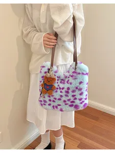 Flauschige Tasche mit violetten Flecken, braunen Riemen und Teddyanhänger, zum weißen Outfit getragen
