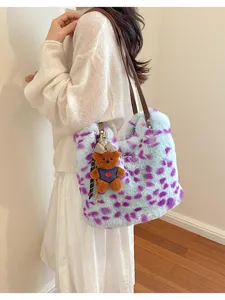 Model trägt eine blaue Plüschtasche mit violetten Flecken, braunen Riemen und Teddyanhänger