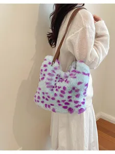 Eine Frau trägt eine flauschige blau-violett gefleckte Tasche mit braunen Henkeln über der Schulter