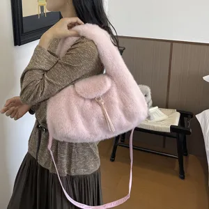Woman modeling a pink plush handbag with a flap, tassel detail and long shoulder strap