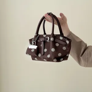 Borsa a secchiello marrone a pois chiari, superficie opaca, manici in pelle scura e fibbia metallica