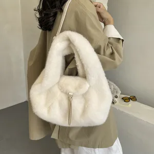 White fluffy faux-fur handbag with metal clasp and tassel, carried on the shoulder by a model