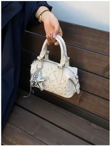 Borsa trapuntata color crema con dettagli brillanti e ciondolo a stella argentato, tenuta dai manici