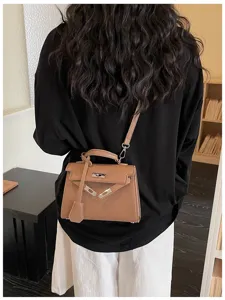 Vista posteriore di una persona con borsa marrone in similpelle goffrata, fibbia argentata e tracolla