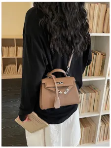 Vista da dietro di una persona con borsa marrone testurizzata con patta e tracolla rimovibile