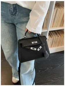 Borsa nera con texture goffrata, portata a mano, con chiusura argentata e tracolla rimovibile