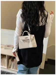 Vista posteriore di una modella con borsa avorio goffrata, catena e fibbia in metallo argentato