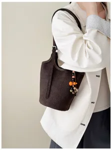 Bolso marrón oscuro al hombro, con relieve de cocodrilo y colgante naranja con cuentas de madera