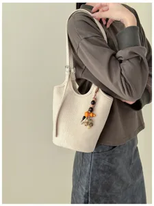Modelo lleva bolso cubo color crema con relieve de cocodrilo, adorno de cuentas y correa ajustable