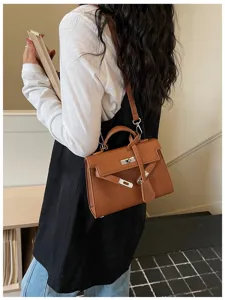 Borsa marrone con patta indossata da una modella, chiusura metallica, manico, tracolla e ciondolo