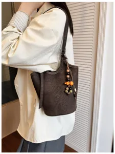 Bolso puesto, marrón oscuro con relieve de cocodrilo, correa larga y adorno de cuentas de madera