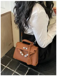 Borsa marrone effetto pelle goffrata indossata a tracolla, con chiusura metallica color argento