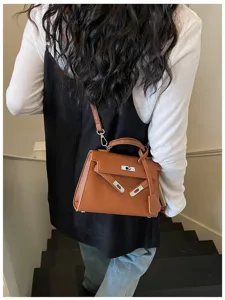 Vista da dietro di una donna con borsa marrone testurizzata, tracolla e chiusura argentata