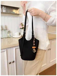 Mujer sostiene un bolso negro con relieve de cocodrilo, correa ajustable y colgante de cuentas