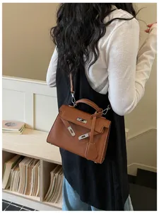 Vista da dietro di una donna con borsa marrone goffrata, dettagli argentati e tracolla