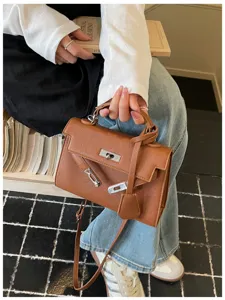 Borsa marrone effetto grana con chiusura argentata e tracolla removibile, tenuta in mano