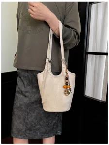 La modelo lleva un bolso cubo color crema con relieve efecto cocodrilo y colgante de cuentas