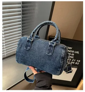 Gros plan sur un sac denim bleu foncé avec deux poignées et une bandoulière amovible