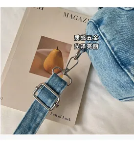 Gros plan sur la bandoulière réglable en denim bleu, avec boucles et clips métalliques argentés.