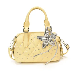 Bolso amarillo acolchado con pedrería, charm de estrella plateado, borla, asa y correa ajustable