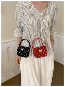 Le modèle porte deux mini-sacs à pois, noir et rouge, avec fermoirs papillon et chaînes dorées