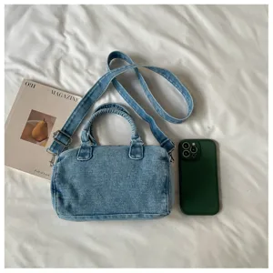 Vue à plat d’un sac en jean bleu clair délavé, anses rondes et bandoulière réglable