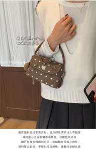 Borsa marrone a pois bianchi, ciondolo a cuore e fiocco, indossata con un outfit
