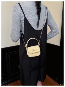 Petit sac jaune à pois avec un nœud, porté sur une chaîne dorée et vu de dos sur un modèle