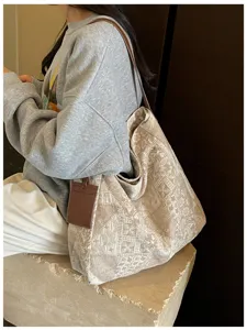 Borsa in jacquard beige portata a spalla, con manici marroni e una piccola etichetta in pelle
