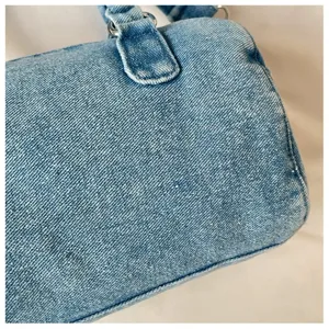 Gros plan sur le sac en denim bleu clair délavé, avec sa texture et l'attache de l'anse