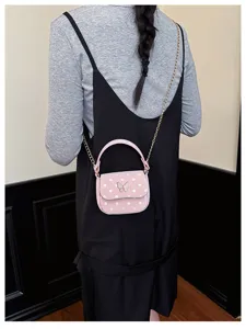 Vue arrière d’un modèle portant un petit sac rose à pois, chaîne dorée et fermoir papillon