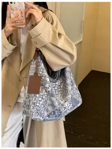 Borsa blu e bianca in tessuto stampato, con manici in pelle marrone, portata a spalla in un selfie.