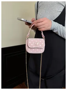 Petit sac rose à pois, avec ornement papillon et chaîne dorée, porté à la taille par un modèle
