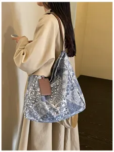Modella con una tote blu e bianca a fantasia, con tracolla in pelle marrone e portacarte appeso