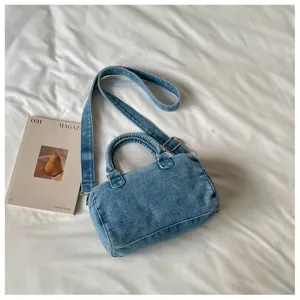 Sac en denim bleu clair délavé, forme arrondie, deux anses et bandoulière réglable, présenté à plat